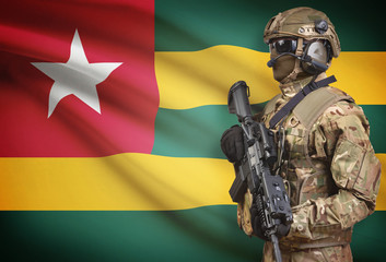 Soldier in helmet holding machine gun with flag on background series - Togo