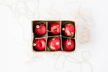box with bright red christmas balls on white background. flat lay, top view