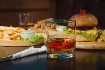 Burgers And Glasses Of Whiskey On Wooden Plates