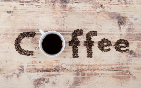 Inscription made from coffe beans and a cup of coffee brew. 