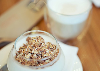 Granola with yogurt and cup of cappuccino; selective focus
