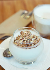 Granola with yogurt and cup of cappuccino; selective focus