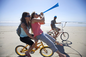 Two women and one man riding bikes, having fun on the beach in San Diego, California.