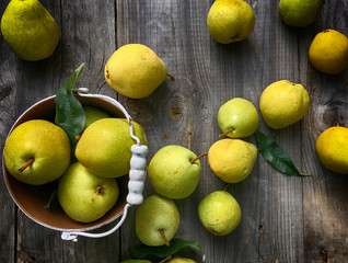 Ripe yellow pear on a gray wooden surface and iron bucket