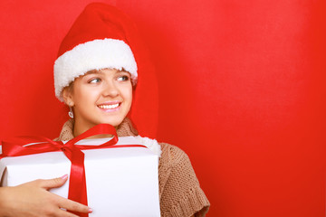 Santa girl holding Christmas gift on red background