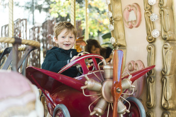 toddler boy sits in carousel airplane