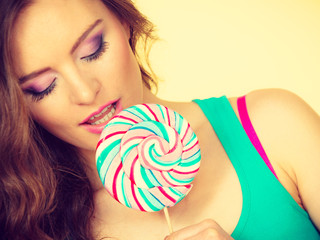 Woman charming girl with lollipop candy