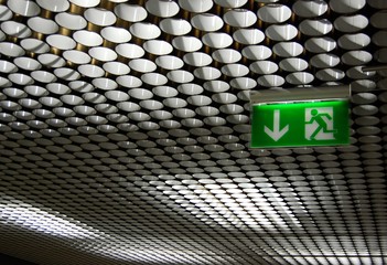 green emergency exit sign on circle pattern ceiling
