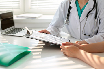 Doctor pointing into medical history form and discussing something with her patient. Close-up.