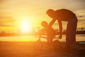 Father took the baby learn to walk at sunset.