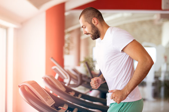 Man running in a modern gym on a treadmill.