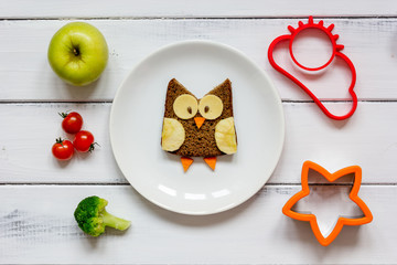 Fototapeta na wymiar kids menu owl shaped sandwich with vegetables and fruits