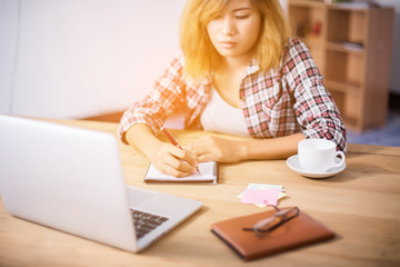 Business Woman Writing with pen in notepad on workplace.