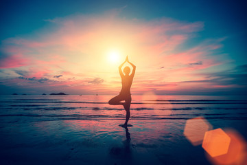 Yoga silhouette. Woman doing meditation near the ocean beach.