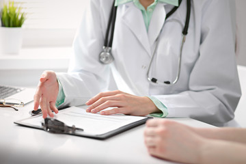 Close up of doctor and  patient  sitting at the desk near the window in hospital