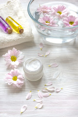 flowers in bowl and oil on wooden background