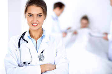 Fototapeta premium Female doctor smiling on the background with patient in the bed