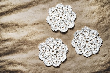 Three handmade white crochet doilies on an old paper background with copy space