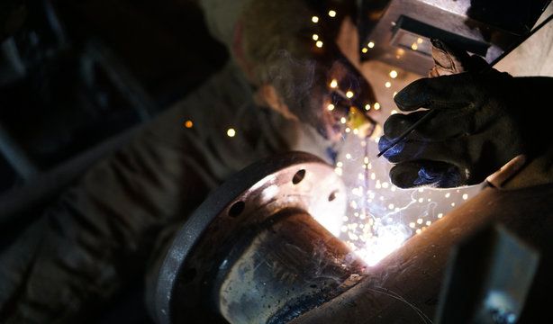 Worker welding metal pipe