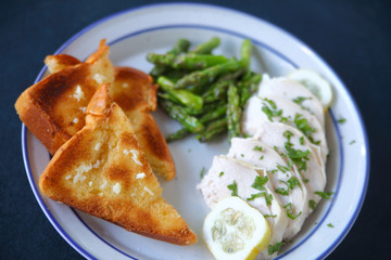 Poached chicken slices with garlic bread and asparagus