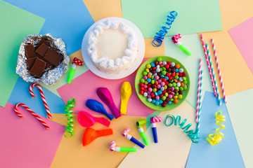 Cake, candy, chocolate, whistles, streamers, balloons on holiday table. Concept of children's...