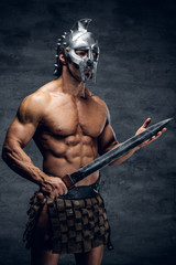 Fototapeta na wymiar A man in a silver gladiator helmet holds an iron sword.
