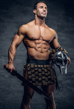Middle age, muscular male holds silver gladiator helmet and an i