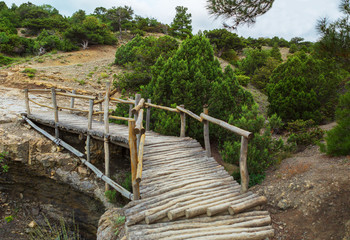 Fototapeta na wymiar Wooden bridge on Trail Golitsyn - Falcon Path a mountain pathway carved at side of Koba-Kaya. Crimea