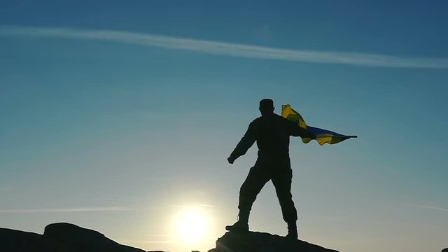 Soldier silhouette, sun and Ukrainian Flag in Slow Motion 