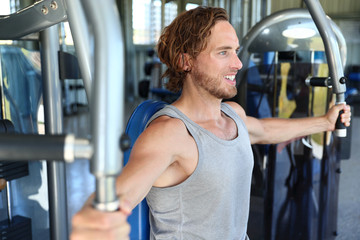 Man at fitness gym. Man doing workout on fitness machine at gym. Gym trainer athlete working out...