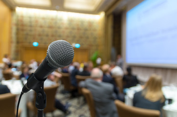 Microphone over the Abstract blurred photo of conference hall or