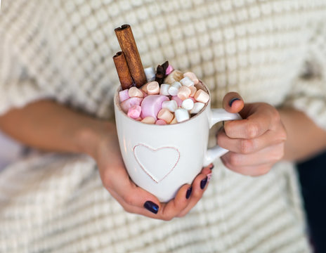 Woman hands holding a cup of hot chocolate with marshmallows