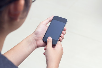 Woman with modern mobile phone in hands touching on a blank scre