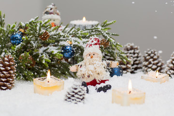 Christmas still life is with snow. Toy Santa Claus is sitting under a Christmas tree.  