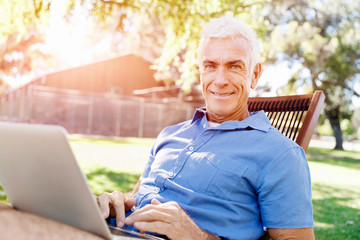 Senior man with notebook sitting in the park