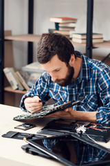 Bearded repairman disassembling computer motherboard. Electronic repair shop, technology, occupation concept © golubovy