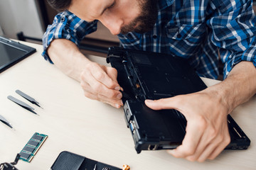 Laptop disassembling with screwdriver at repair. Engineer separate computer inside components from...