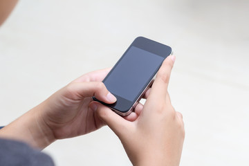 Woman with modern mobile phone in hands touching on a blank scre