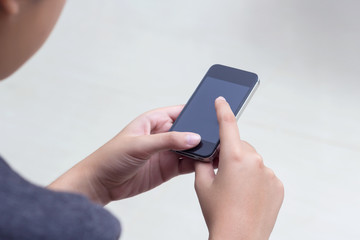 Woman with modern mobile phone in hands touching on a blank scre