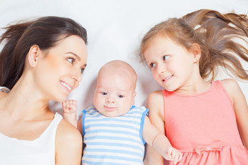 Happy family of mother with daughter looking at baby