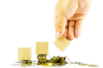 Hand holding blank wooden block with stacked coins