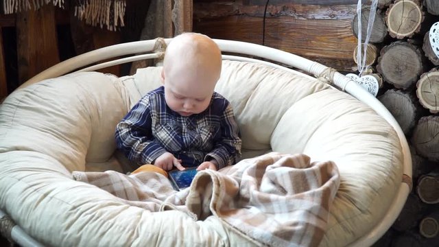 Baby sitting in a chair playing in phone