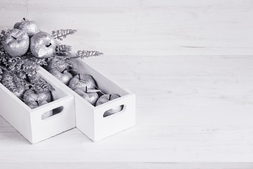 Christmas soft silver decorations in white boxes on a white wooden background. Xmas background.