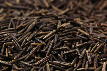 Black rice close-up background. Heap wild brown unpolished rice for vegetarians.