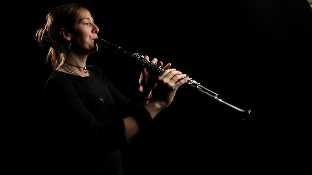 woman playing the clarinet in a dark room