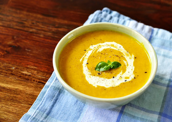 Bowl with pumpkin soup and copy space. Cream soup on a white wooden table.