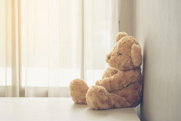 Teddy bear sitting on wooden desk in room with copy space