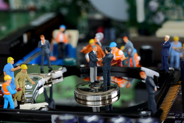 Selective focus of miniature business man handshake on the disk of harddisk as commitment, repiar and industrial concept.