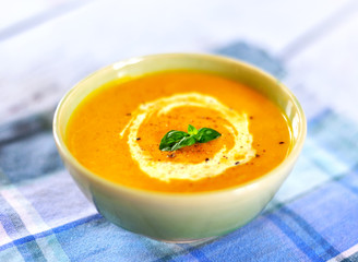 Bowl with pumpkin soup and copy space. Cream soup on a white wooden table.