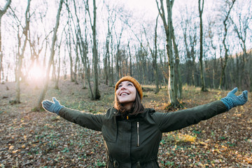 Young woman meditating with open arms standing in winter forest